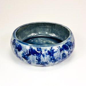 Könnte beinhalten: Eine blaue und weiße Keramikschüssel mit strukturierter Oberfläche. Die Schüssel hat eine runde Form und einen breiten Rand.