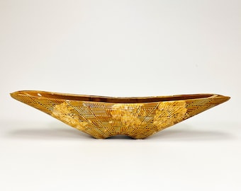 May include: A brown ceramic bowl with a geometric pattern. The bowl is shaped like a boat and has a wide, shallow opening.