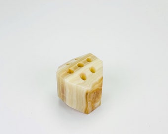 May include: A white and brown marble pen holder with six holes. The holder is shaped like a hexagon.