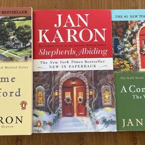 May include: Three paperback books by Jan Karon, part of the Beloved Mitford series. The books are titled "At Home in Mitford", "Shepherds Abiding", and "A Common Life: The Wedding Story".