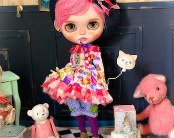 May include: A pink haired doll wearing a black beret, a colorful dress, and purple tights. The doll is standing on a black and white checkered floor with a teddy bear and a pink cat toy.