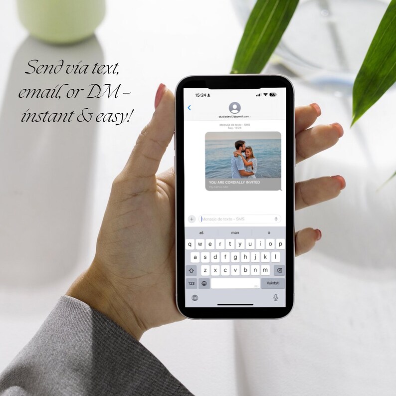 Op de afbeelding: Een smartphone toont een sms-uitnodiging met een foto van een stel. Het scherm toont de tekst "YOU ARE CORDIALLY INVITED". De telefoon wordt vastgehouden door een persoon met rode nagellak. De tekst "Send via text, email, or DM - instant & easy!" is ook zichtbaar.