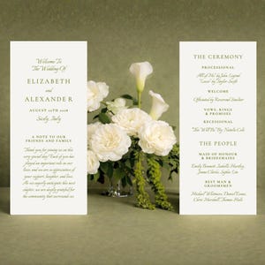 May include: Two ivory wedding ceremony programs with text, flanking a vase of white flowers. The left program reads "Welcome to the Wedding Of Elizabeth and Alexander, August 26th 2018, Sicily, Italy." The right program lists the ceremony details.