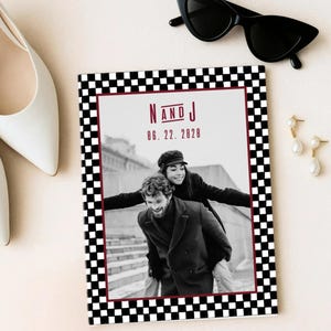 Può includere: Un invito di nozze con un bordo a scacchi in bianco e nero e una foto di una coppia. Il testo "N AND J" e la data "06. 22. 2028" sono in bordeaux. Sono visibili anche occhiali da sole neri e orecchini.