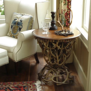 May include: A wooden table with a unique antler base. The table has a brown top and is decorated with a pair of antlers and a candlestick.