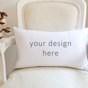May include: White pillow with the text "your design here" on a white armchair with a cotton branch in a glass vase.
