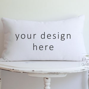 May include: White rectangular pillow with the text "your design here" on a white distressed wooden table.