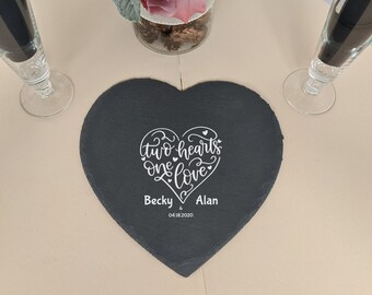 Puede incluir: Un posavasos de pizarra negro en forma de corazón con el texto "two hearts one love" y los nombres "Becky & Alan" y la fecha "04.18.2020" en letras blancas.