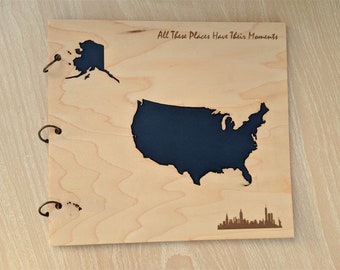 May include: A wooden photo album with a map of the United States of America on the front. The album has three metal rings for holding photos. The text "All These Places Have Their Moments" is engraved on the front of the album.