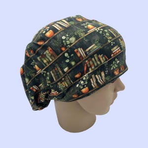 May include: A green scrub hat with a bookshelf print featuring books, plants, and orange pots.