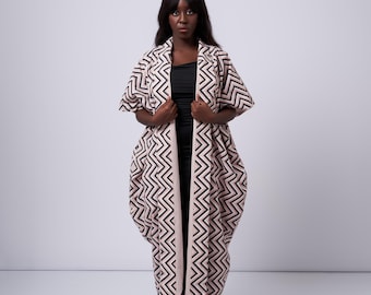 May include: A long, flowing, pink and black patterned robe with a chevron design. The robe has a long, flowing silhouette and is open in the front.