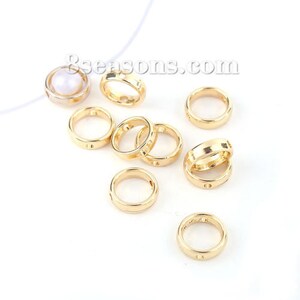 May include: A collection of ten gold-colored metal jump rings, each with a small hole in the center. The rings are of varying sizes, with some being slightly larger than others.