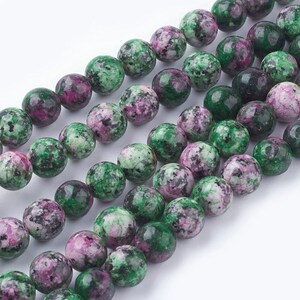May include: A strand of green and pink gemstone beads. The beads are round and have a mottled appearance.