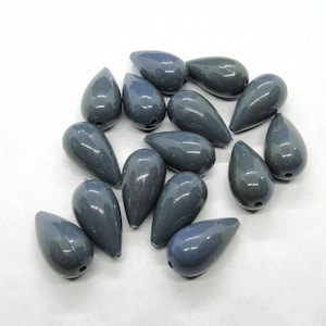 Peut inclure: Un ensemble de 15 perles de verre grises en forme de goutte. Les perles sont lisses et brillantes.