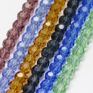 May include: Assortment of faceted glass beads in various colors, including purple, blue, green, brown, and black. The beads are strung together in rows, creating a colorful and eye-catching display.