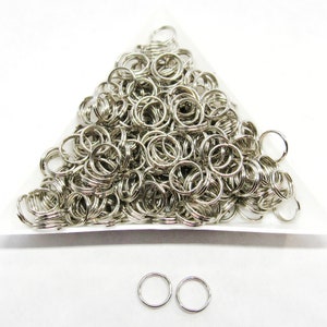 May include: A large pile of silver jump rings, with two smaller jump rings in the foreground.