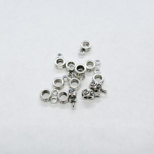 May include: Silver-toned metal bead caps with a swirl design. The bead caps have two loops on one side and a single loop on the other side.