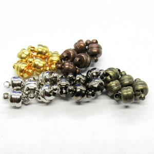 May include: Three sets of magnetic clasps in silver, gold, and bronze. Each clasp is made of two round pieces with a small hole in the center.