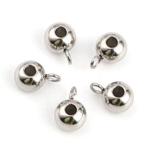 May include: Five shiny, silver-colored metal ball beads with a loop and a hole. These beads are round and have a polished finish, perfect for jewelry making or crafting projects.