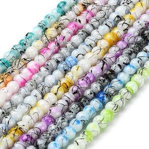 May include: Assortment of colorful glass beads with black swirl designs. The beads are round and have a glossy finish.