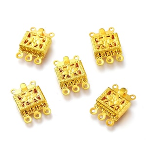 May include: Five gold-tone metal clasps with a decorative floral design. Each clasp has three loops for attaching jewelry.