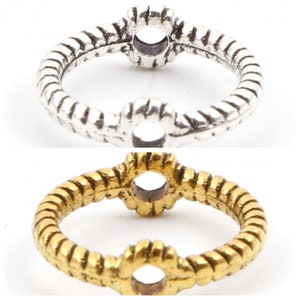 May include: Two silver and gold rings with a round opening in the center. The rings are made of twisted metal and have a decorative design.