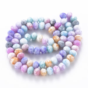 May include: A strand of colorful faceted glass beads in shades of pink, blue, purple, and orange. The beads are strung on a clear thread and are arranged in a circular pattern.