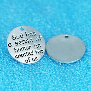 May include: Two silver metal charms. One charm has the text "God has a sense of humor he created two of us".