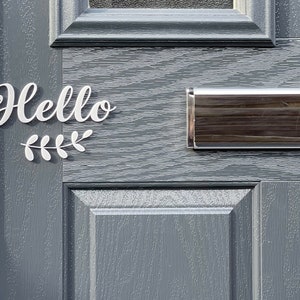 May include: A grey front door with a white "Hello" sign and a silver letterbox.