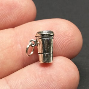 Puede incluir: Encanto de plata en forma de taza de café para llevar. El encanto está detallado con una tapa y un diseño de taza texturizado.