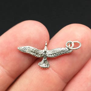 Könnte beinhalten: Silberner Anhänger einer fliegenden Möwe mit einem Sprungring zum Anbringen an einer Halskette oder einem Armband.