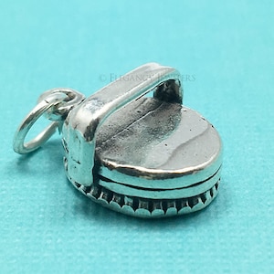 May include: Silver charm in the shape of a vintage record player. The charm has a detailed design and a loop for attaching to a bracelet or necklace.