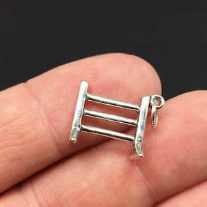 May include: Silver charm in the shape of a three-rail fence. The charm has a loop at the top for attaching to a bracelet or necklace.
