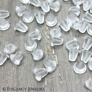 May include: A large quantity of clear plastic earring backs. The backs are small and have a rounded top. They are designed to be used with stud earrings.