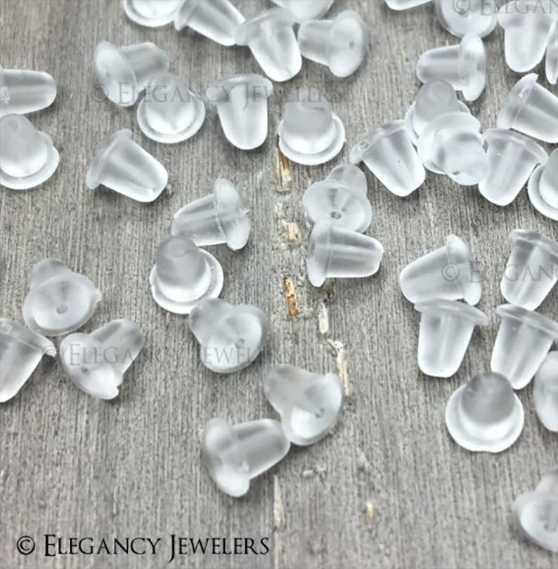 May include: A large quantity of clear plastic earring backs. The backs are small and have a rounded top. They are designed to be used with stud earrings.