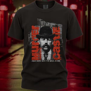 May include: Black t-shirt featuring a vintage portrait of a man with a mustache and bowler hat. The text "MURDER CASTLE" is printed in red, along with the phrase "I WAS BORN WITH THE DEVIL IN ME".