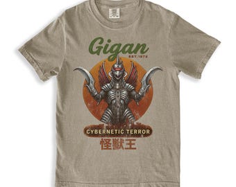 May include: A tan t-shirt featuring a graphic of Gigan, a cybernetic monster, with the text "Gigan EST.1972" above the monster and "CYBERNETIC TERROR" and Japanese text below. The monster is set against an orange circle.