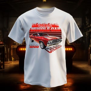 May include: White t-shirt featuring a red 1969 Chevrolet muscle car graphic. The design includes the words "CHEV-HELL-RAISER" and "MUSCLE CAR" in red, with a flame-like design above the car and the word "CHEVROLET" below.