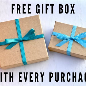 A free gift box is included with the purchase of a pair of earrings. The image shows two nice jewelry boxes tied with blue ribbons.