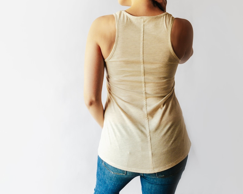 May include: A light beige sleeveless tank top with a scoop neck and a straight hemline. The tank top is made of a soft, comfortable fabric and has a relaxed fit.