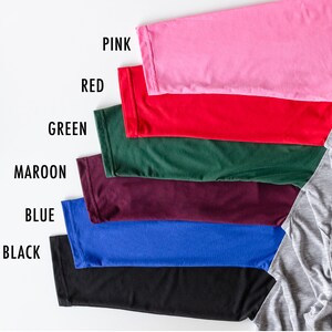 May include: A set of seven fabric swatches in various colors, including pink, red, green, maroon, blue, black, and gray. The swatches are arranged in a row from top to bottom, with the gray swatch at the bottom right.
