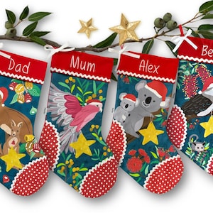 May include: Four festive Christmas stockings featuring Australian wildlife, such as a kangaroo and koalas, all adorned with Santa hats. The teal stockings have red polka dot trim and are personalised with names.