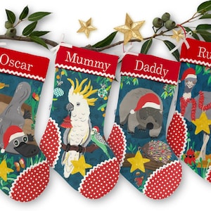 May include: Four Christmas stockings with red tops and white scalloped edges, each featuring a different Australian animal: a platypus, cockatoo, wombat, and emu. The stockings are decorated with a teal background and red polka dot trim.