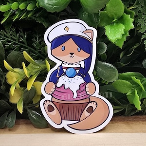 May include: A cartoon sticker of a blue and white fox wearing a blue and white hat holding a pink and white cupcake with blue frosting and white sprinkles.