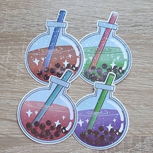 May include: Four round glass bottles with colorful liquid and boba pearls inside. Each bottle has a straw sticking out of the top. The bottles are decorated with glitter and stars.