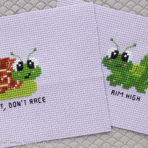 May include: Two cross-stitch embroidery patterns featuring cute cartoon animals. The first pattern shows a snail with the text "Rest, Don't Race". The second pattern shows a caterpillar with the text "Aim High".