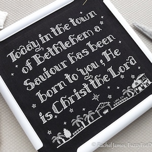 May include: Black embroidery hoop with white text that reads "Today in the town of Bethlehem a Saviour has been born to you, He is Christ the Lord."  The text is surrounded by small white stars and a white illustration of a town with a star above it.