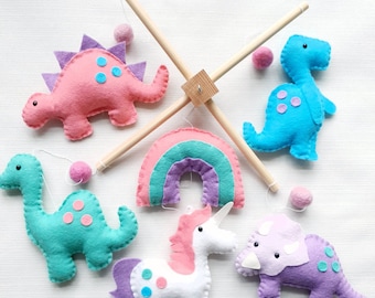 Unicorn and dinosaur mobile on a wooden frame with felt balls with rainbow in bright pink, blue and purple felt.