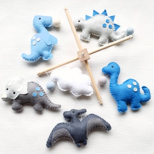 Blue and grey dinosaur mobile on a wooden frame with felt balls