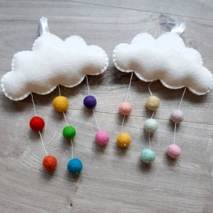 May include: Two white felt clouds with rainbow coloured felt balls hanging from them. The balls are in a rainbow order, starting with red and ending with purple.